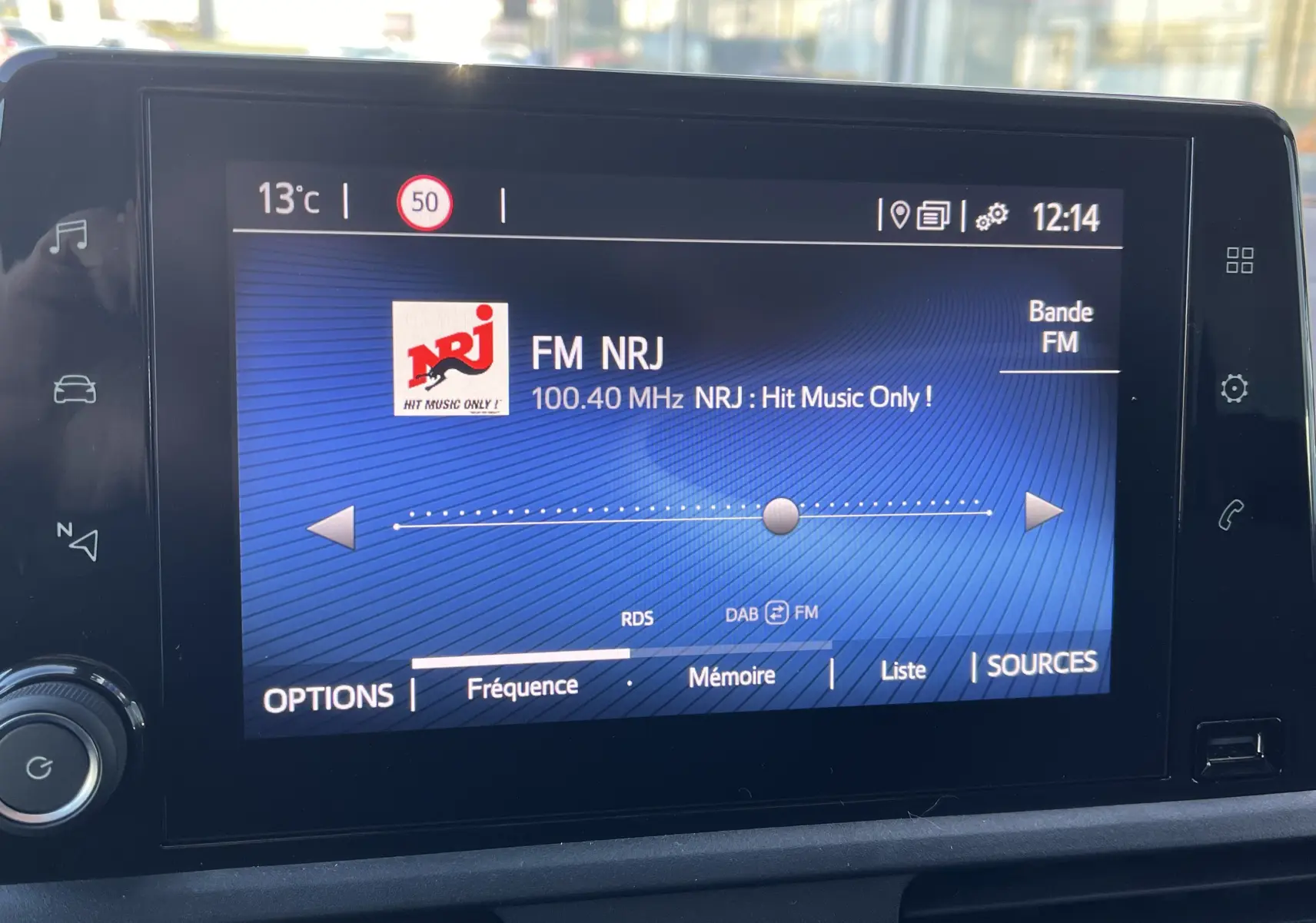 Écran tactile central du Toyota Proace City blanc glacier affichant la radio FM NRJ à 100,40 MHz en intérieur véhicule.