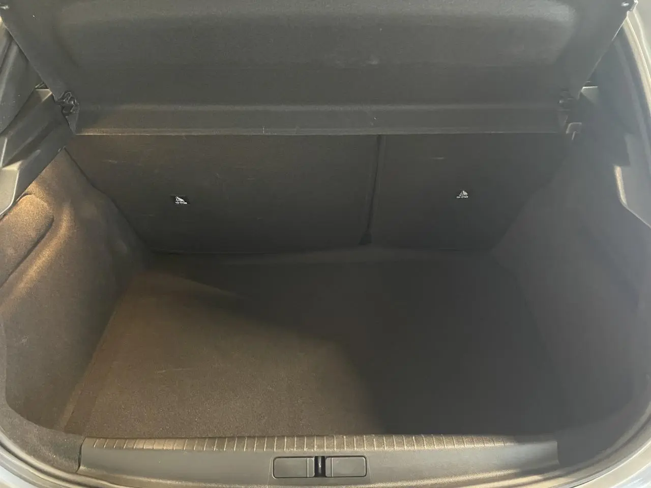 Coffre ouvert de la Peugeot 208 gris clair, vue intérieure montrant l’espace de rangement vide.