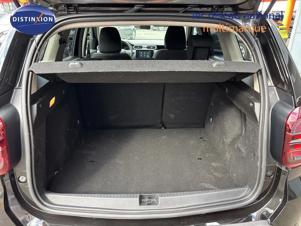 Coffre ouvert vu de l'arrière d'un Dacia Duster noir 2024, montrant l'espace de chargement vide et la plage arrière relevée.