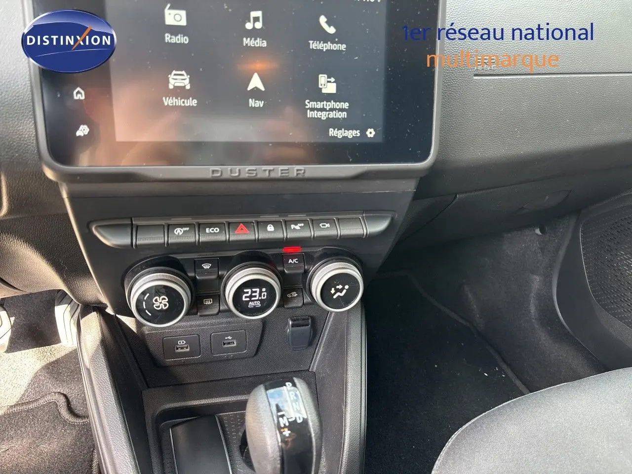 Vue intérieure centrée sur la console centrale du Dacia Duster noir 2024, avec écran tactile et commandes climatisation.