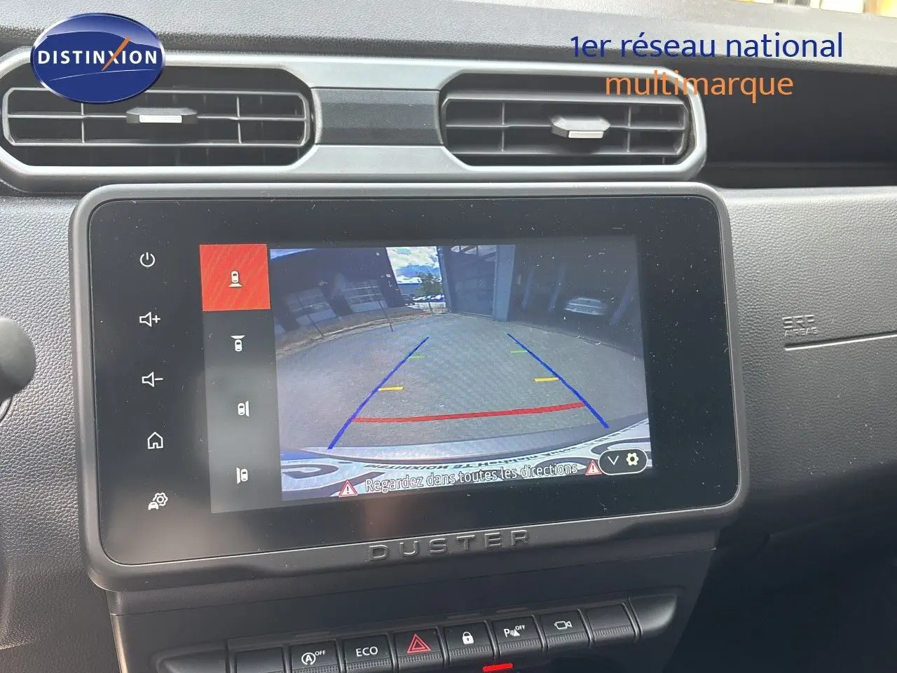 Écran tactile central du Dacia Duster noir 2024 montrant la caméra de recul avec lignes de guidage colorées.