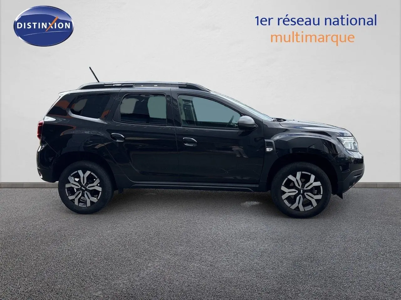 Profil latéral droit du Dacia Duster Journey TCe 150 EDC noir 2024 avec jantes bi-ton et toit équipé de barres de toit.