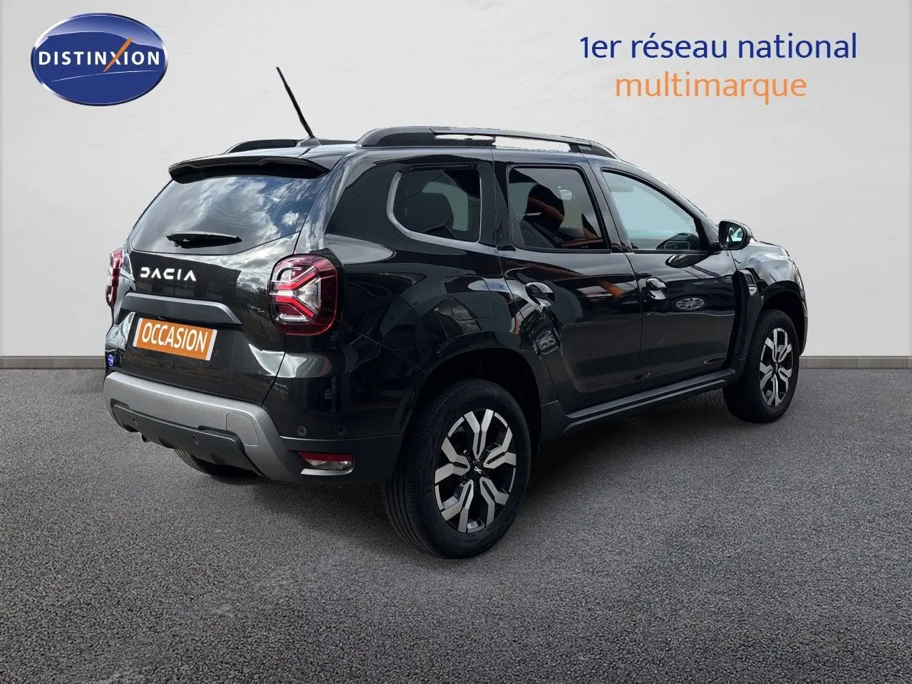 Dacia Duster noir en 3/4 arrière droit, SUV compact avec jantes bi-ton et toit avec barres de toit.