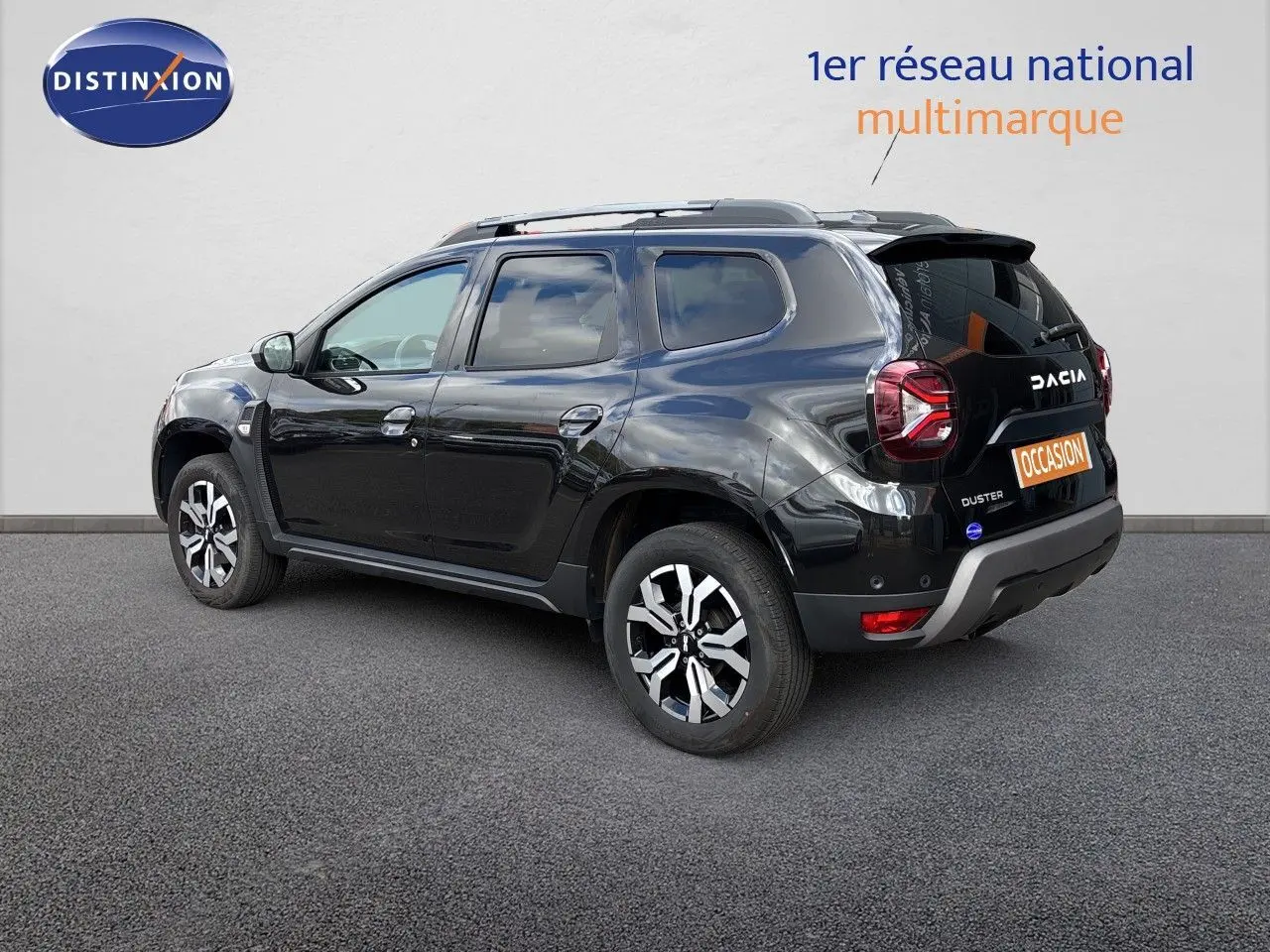 Vue 3/4 arrière droite d'un Dacia Duster noir 2024 avec jantes bicolores et détails chromés sur carrosserie.