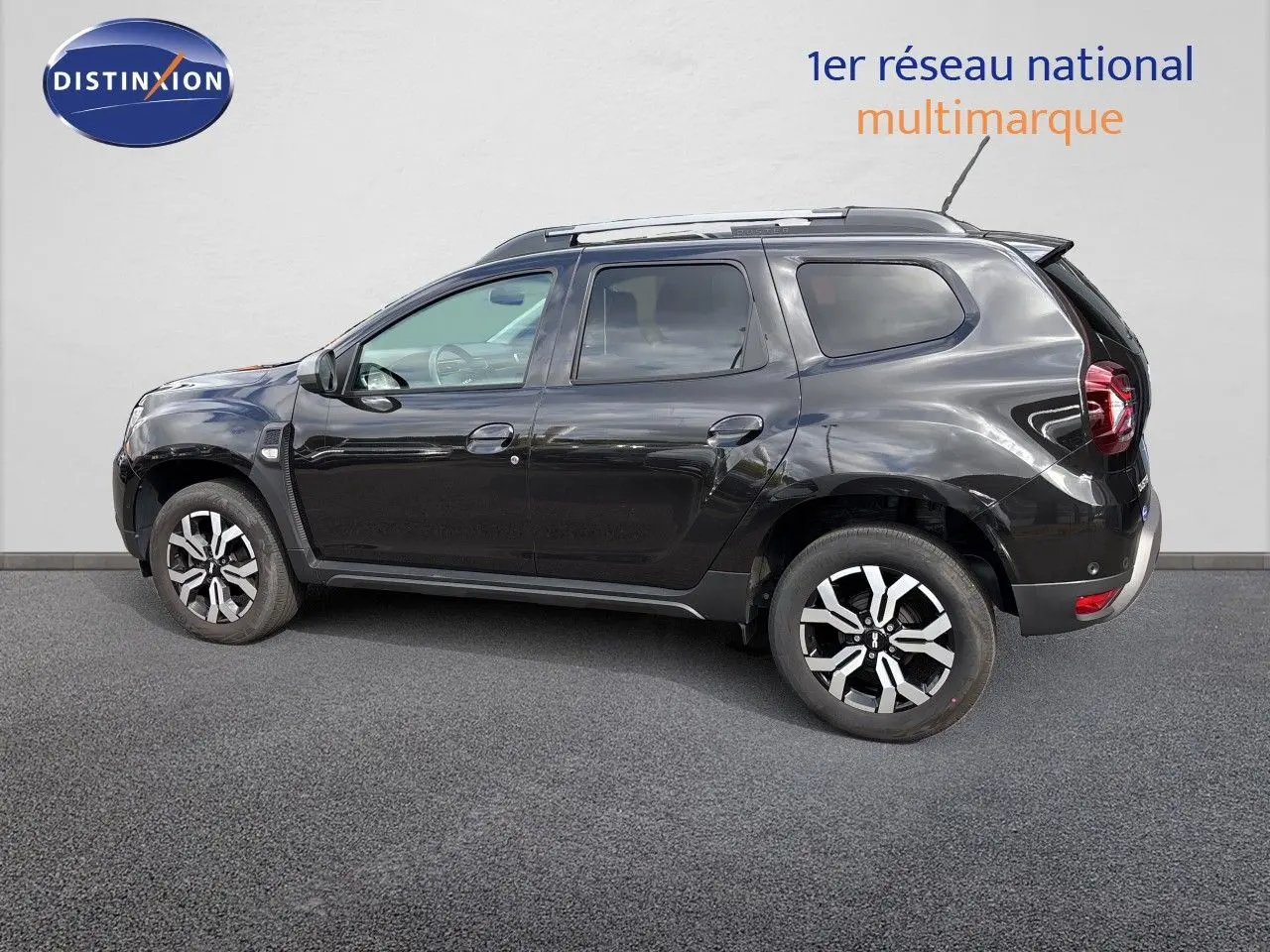 Profil droit du Dacia Duster Journey TCe 150 EDC noir 2024 avec jantes biton et barres de toit visibles.