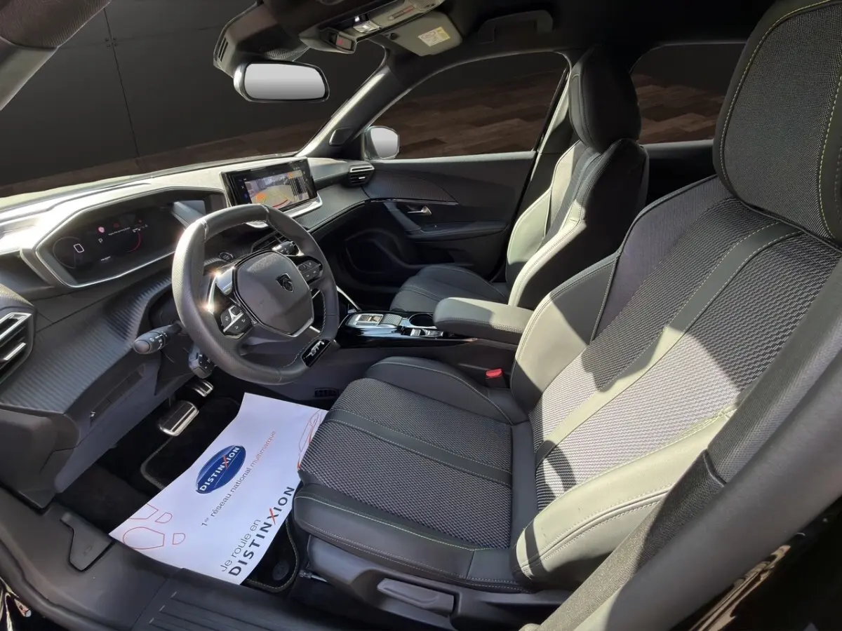 Vue intérieure côté conducteur du Peugeot 2008 Hybrid 145 e-DCS6 GT 2026 avec sièges cuir noirs et tableau de bord numérique.