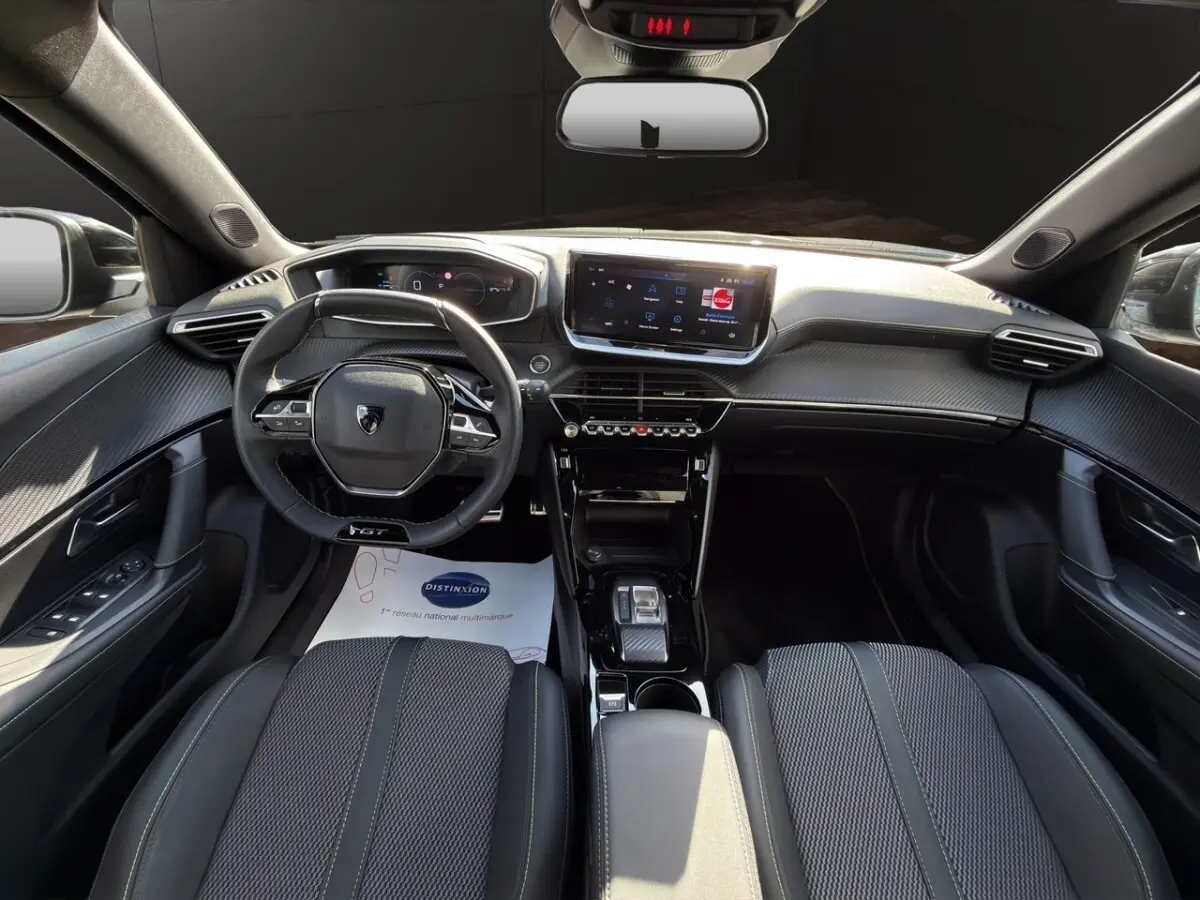 Intérieur noir du Peugeot 2008 Hybrid 145 GT vu de face, volant cuir multifonctions et écran tactile central.