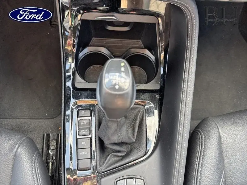 Le levier de vitesses automatique noir et les commandes de mode de conduite dans l'habitacle d'une BMW X1 Saphirschwarz.