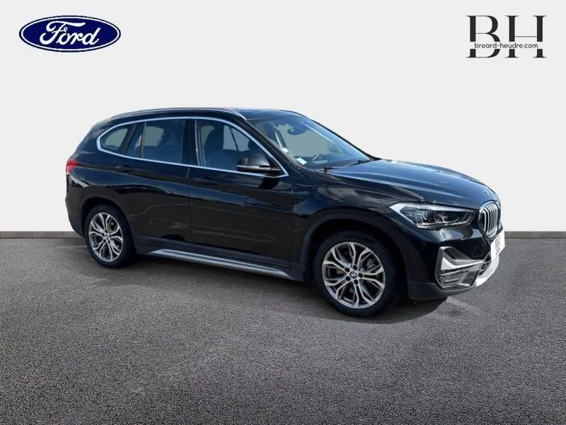 BMW X1 xDrive25eA 220ch xLine 2021 en Saphirschwarz, vue 3/4 avant côté gauche avec jantes alu distinctives.