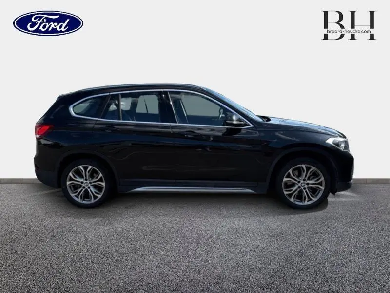 Profil côté gauche d'un BMW X1 xDrive25eA 220ch xLine 2021 en noir saphir avec jantes alliage et vitres teintées.