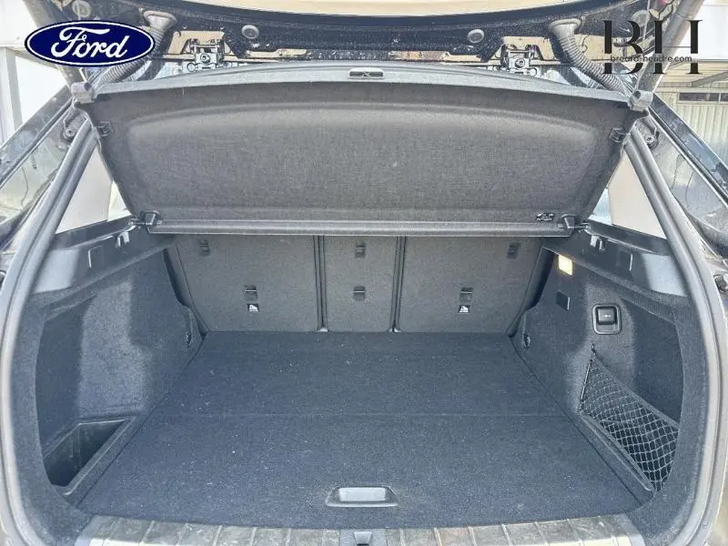 Coffre ouvert vu de l'arrière d'un BMW X1 xDrive25eA 2021 noir Saphirschwarz, espace de chargement vide et tapis noir.