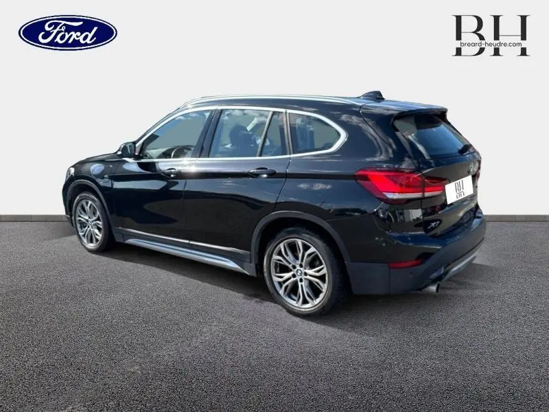 BMW X1 xDrive25eA 220ch xLine 2021 en Saphirschwarz, vue 3/4 arrière droit avec jantes alu et feux LED arrière.