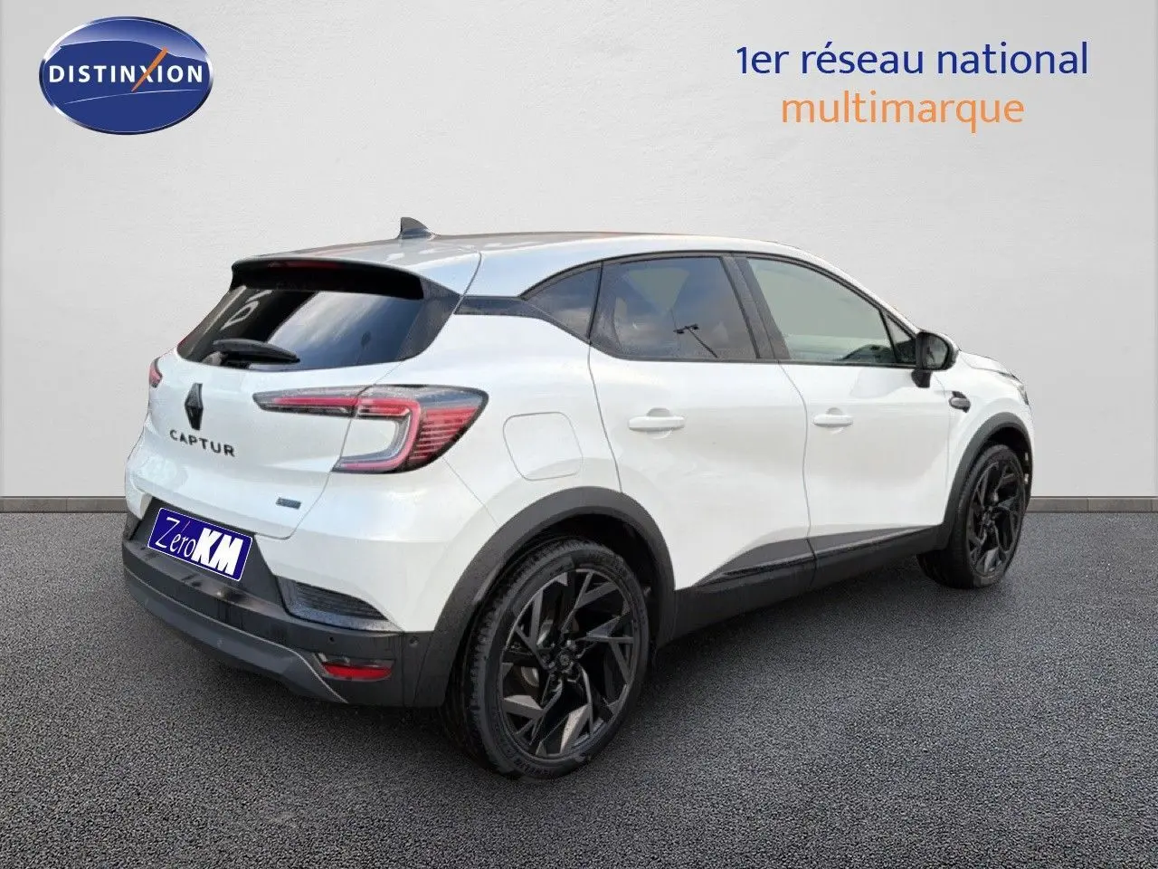 Vue 3/4 arrière droite du Renault Captur blanc nacré avec toit gris et jantes noires distinctives.