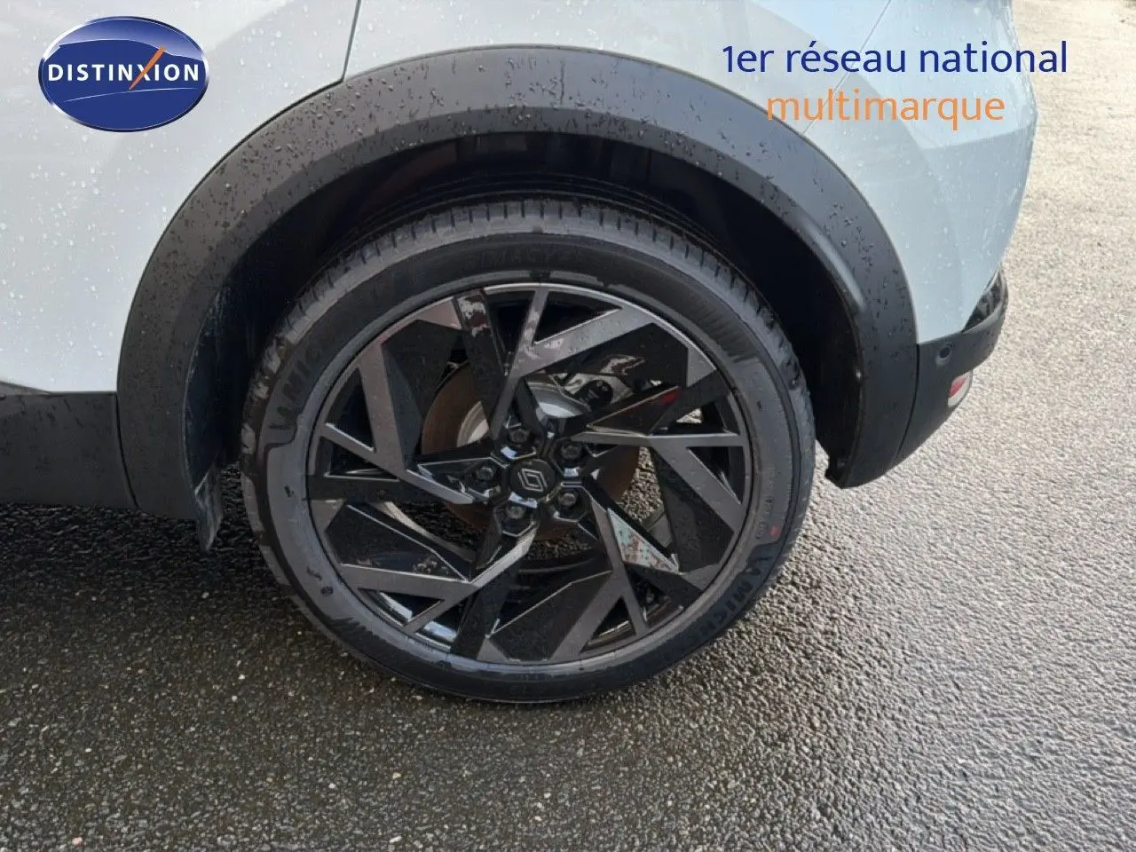 Gros plan sur la roue arrière droite d’un Renault Captur blanc nacré avec jante noire au design géométrique.