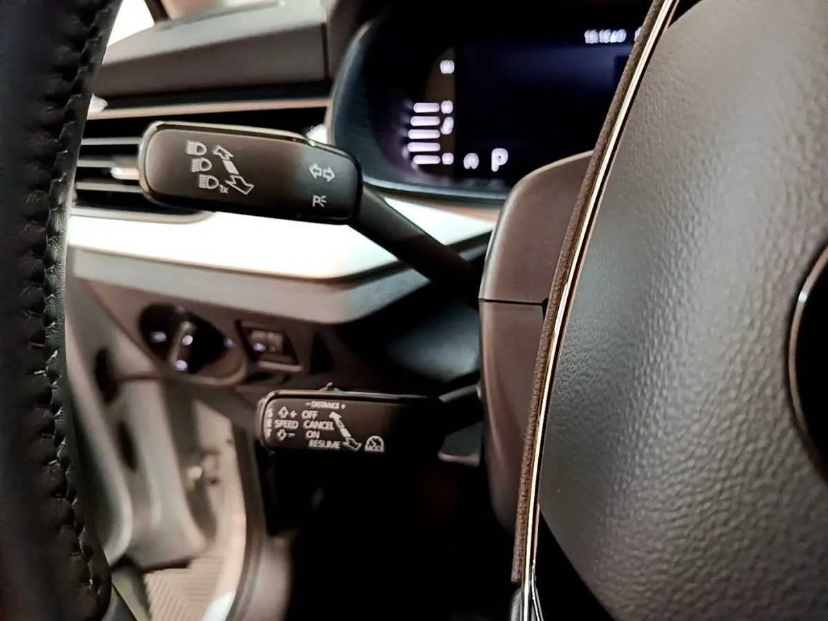 Gros plan sur les commandes au volant du Skoda Kamiq 2022, intérieur gris clair avec affichage numérique flou.