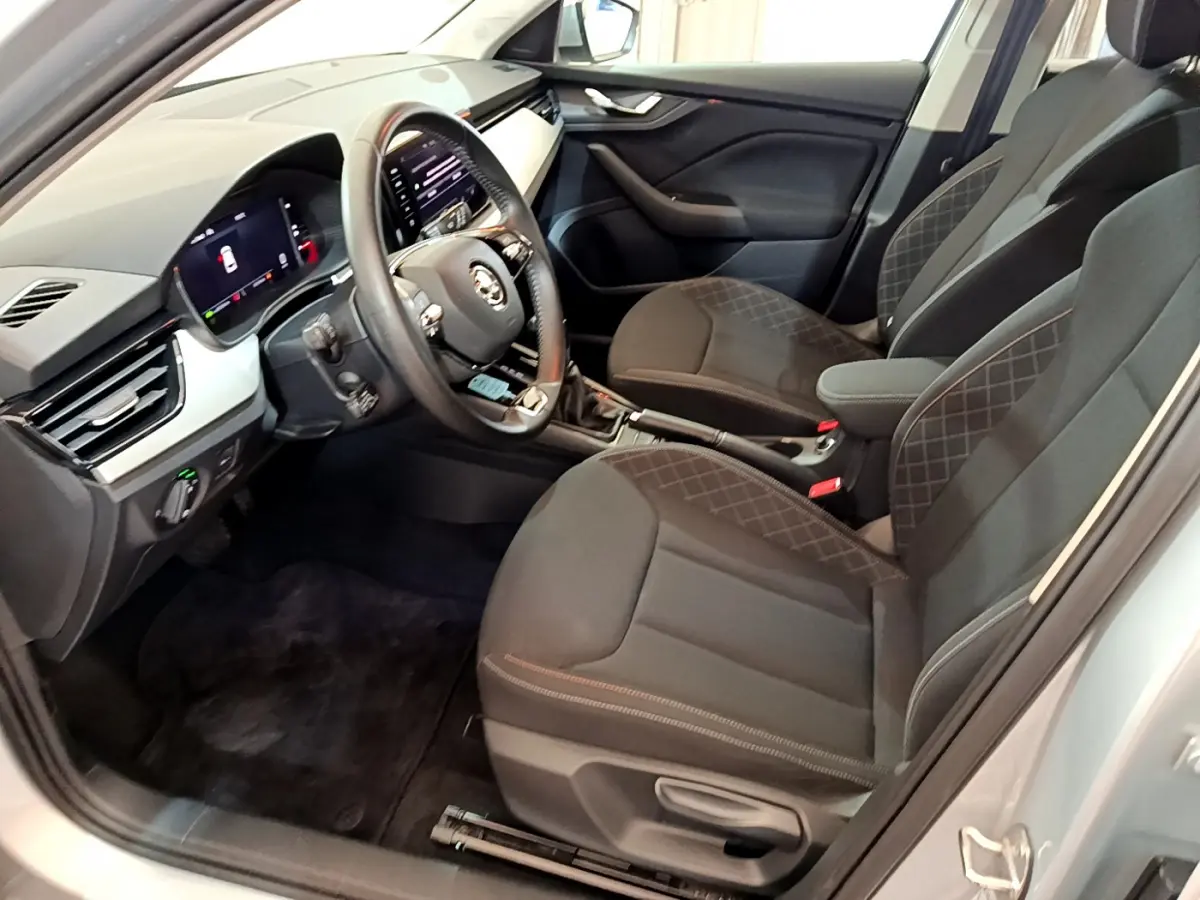 Intérieur avant droit du Skoda Kamiq gris clair 2022 avec sièges noirs et tableau de bord digital lumineux.