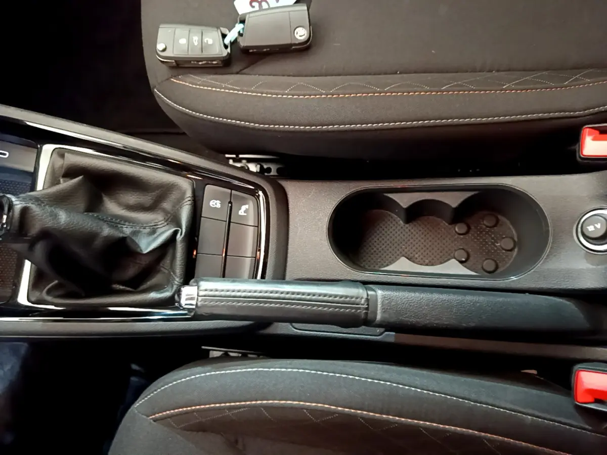 Vue plongeante sur la console centrale noire du Skoda Kamiq 2022, avec levier de frein à main et porte-gobelets.