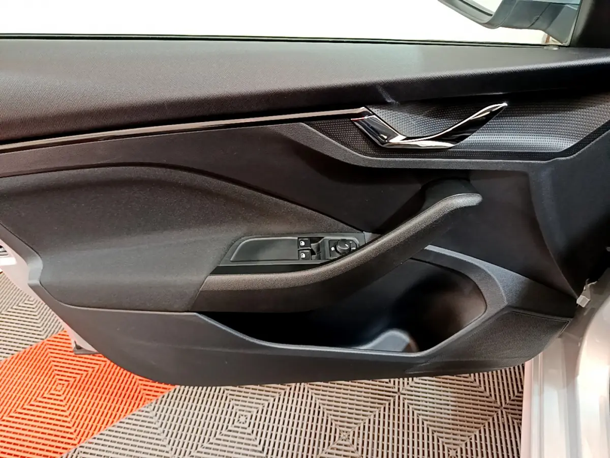 Vue rapprochée de la porte côté conducteur du Skoda Kamiq gris clair 2022 avec commandes électriques et poignée noire.