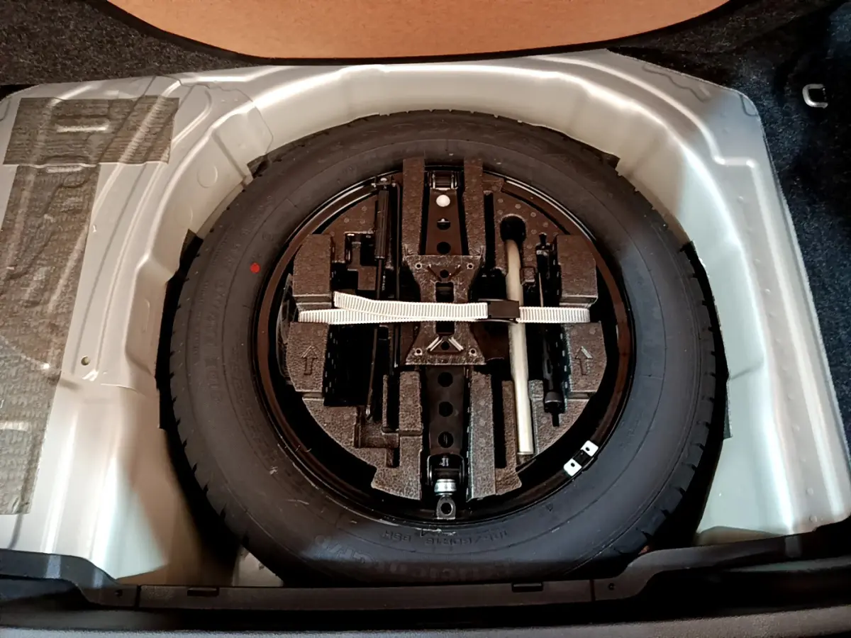 Roue de secours galette noire avec kit de réparation dans le coffre gris clair d'une Skoda Kamiq 2022.