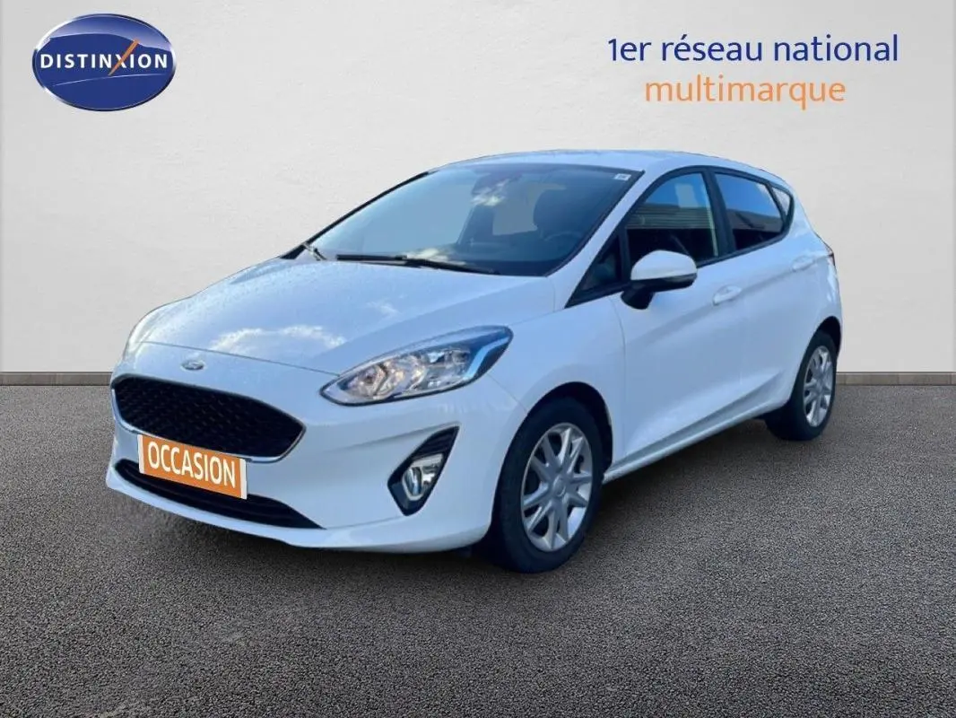 Ford Fiesta blanche vue en 3/4 avant droit, avec jantes classiques et vitres surteintées.