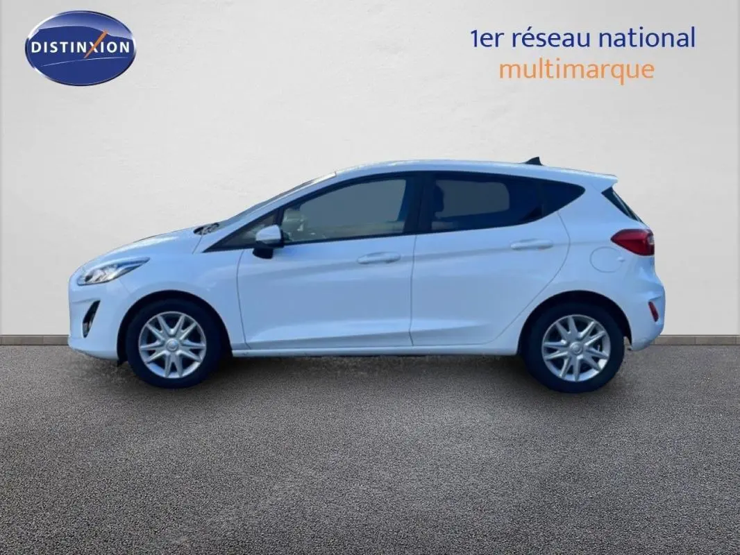 Vue de profil côté gauche d'une Ford Fiesta blanche 2020 avec vitres surteintées et jantes classiques 15 pouces.