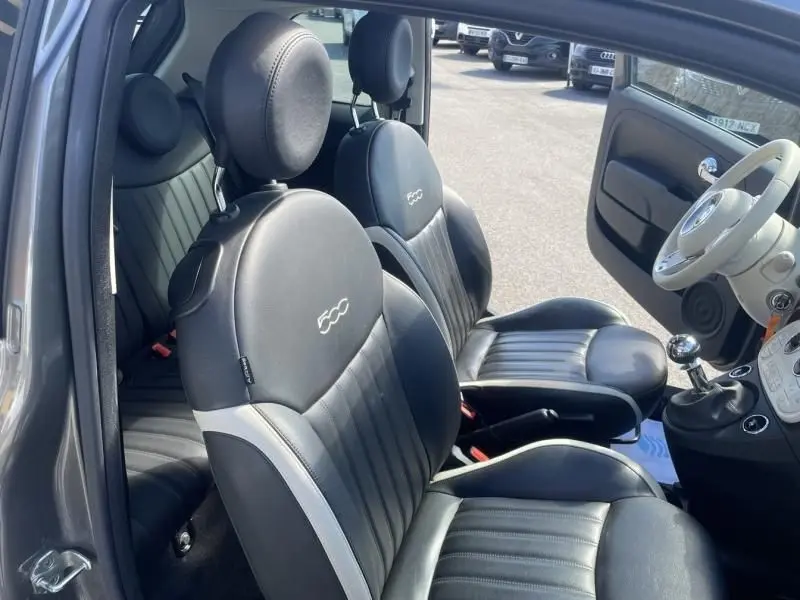 Vue intérieure côté gauche de la Fiat 500 gris foncé 2019, mettant en valeur les sièges en cuir noir avec logo 500 brodé.