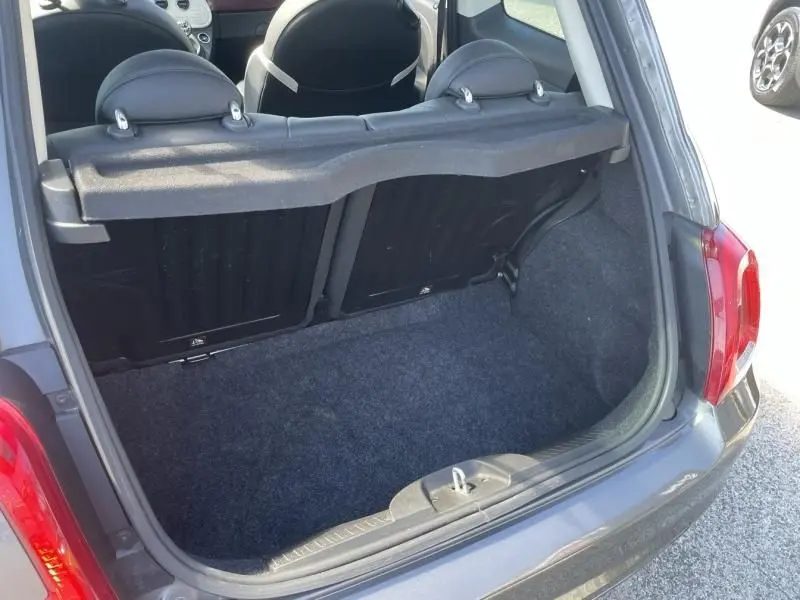Vue arrière ouverte sur le coffre d'une Fiat 500 gris foncé 2019, montrant l'intérieur et les sièges arrière.