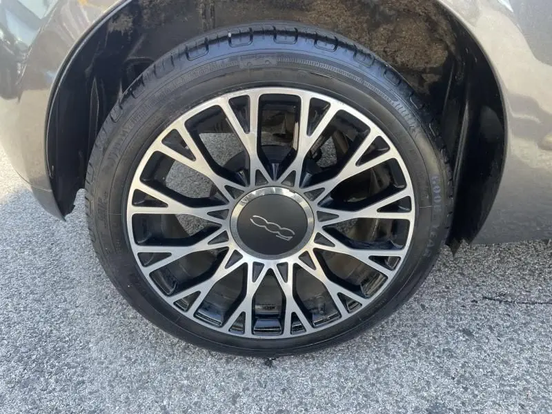 Gros plan sur la roue avant droite gris foncé d'une FIAT 500 1.2 69 cv Club avec jante alliage à motif étoilé.