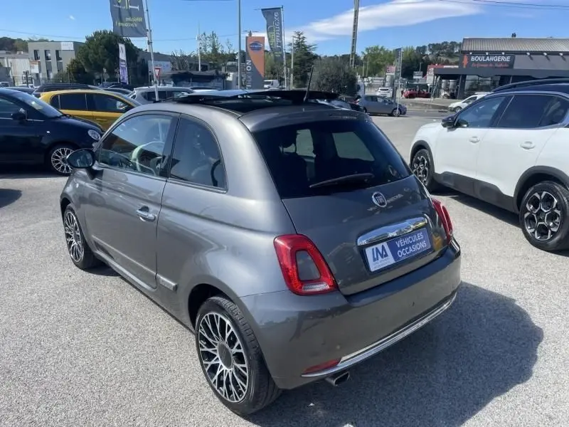 Vue 3/4 arrière droite d'une Fiat 500 gris foncé 2019 avec toit ouvrant et jantes alliage distinctives.