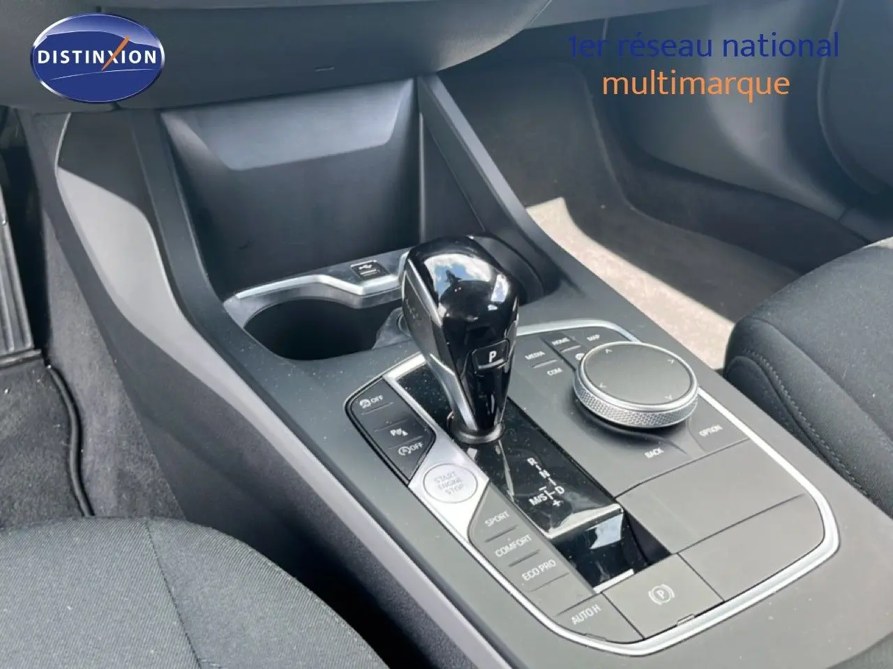Vue rapprochée de la console centrale de la BMW Série 1 116i 2022, avec levier de vitesse automatique noir brillant.