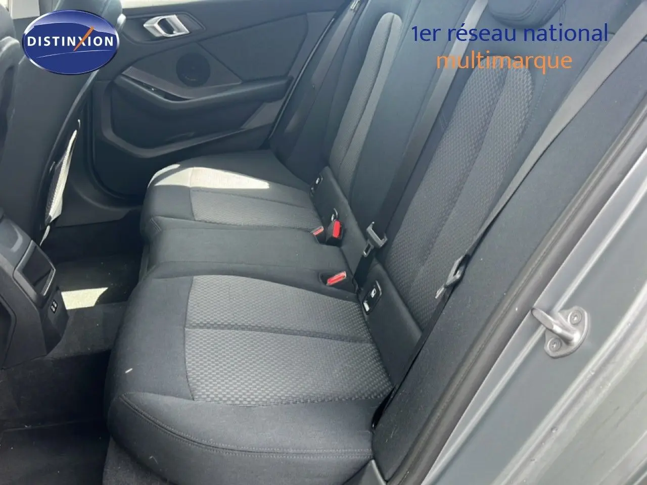 Vue intérieure côté arrière droit de la BMW Série 1 116i 2022 avec sièges tissu gris et portières assorties.