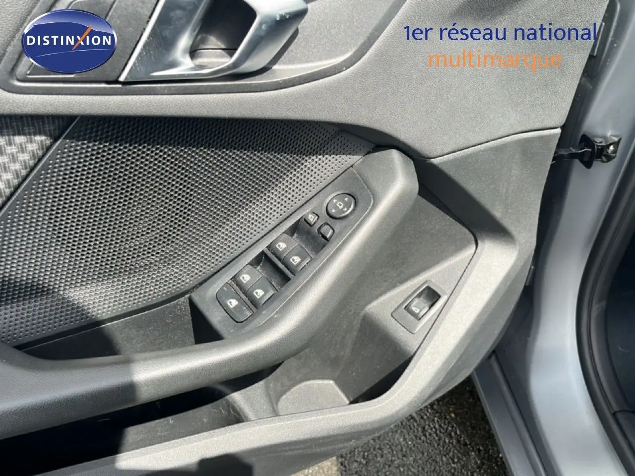 Gros plan sur la porte avant gauche grise d'une BMW Série 1 116i, montrant les commandes de vitres et rétroviseurs.