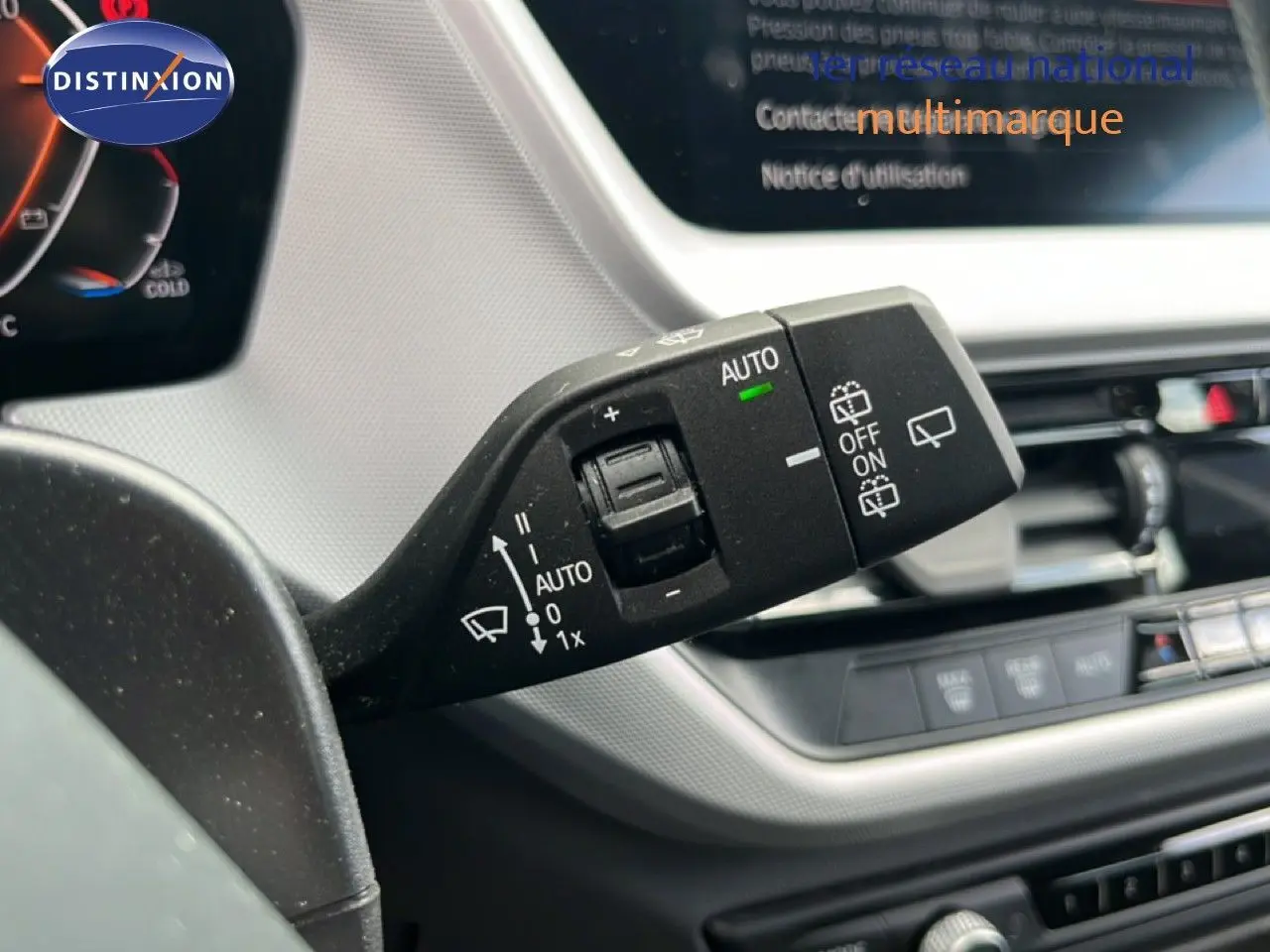 Gros plan sur la commande d’essuie-glace à gauche du volant dans l’habitacle gris et noir d’une BMW Série 1 116i 2022.