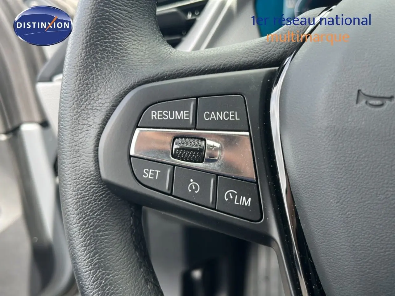 Gros plan sur les commandes de régulateur de vitesse au volant cuir noir d'une BMW Série 1 116i 2022.