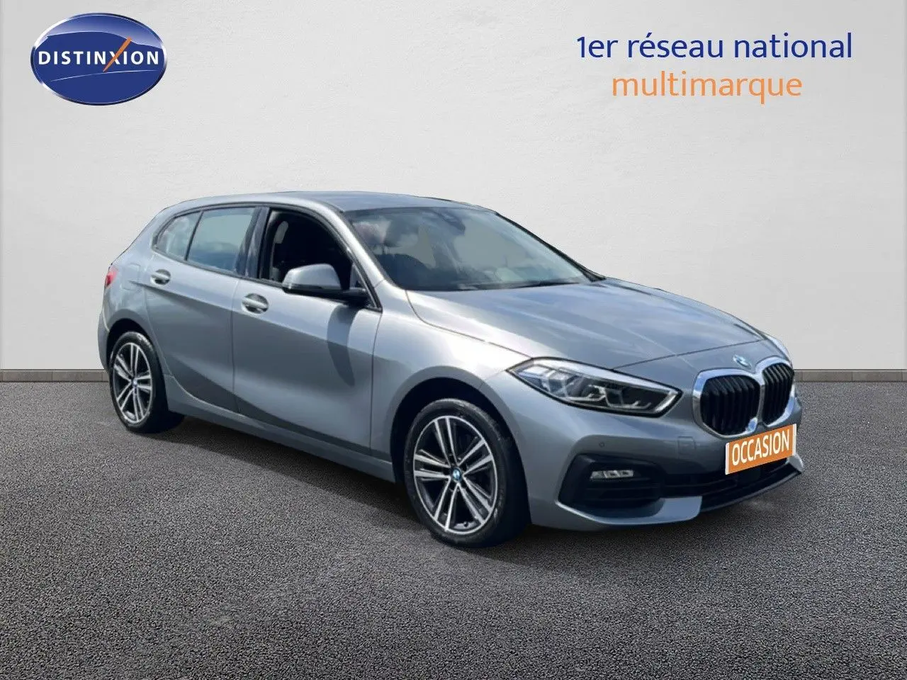 BMW Série 1 116i 2022 en Frozen Pure Grey vue 3/4 avant droit avec calandre noire et jantes bi-ton.