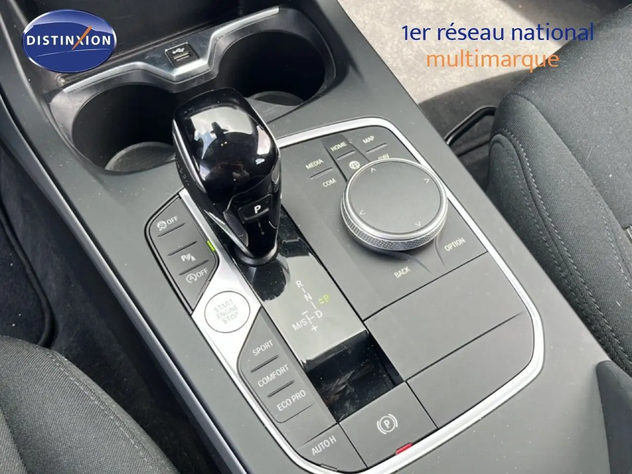 Gros plan sur la console centrale de la BMW Série 1 116i 2022, avec levier de vitesse noir brillant et commandes de mode de conduite.