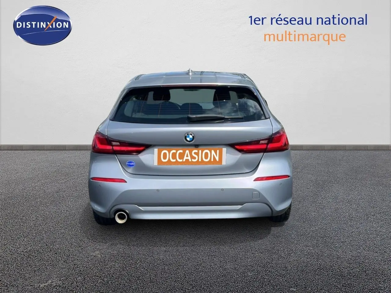 Vue arrière d'une BMW Série 1 116i 2022 en gris Frozen Pure Grey avec feux arrière LED et sortie d'échappement côté gauche.