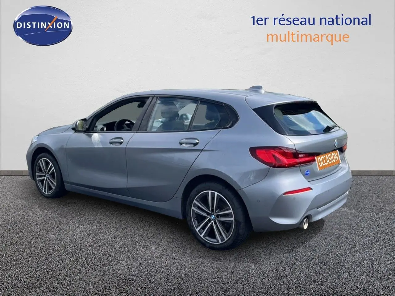 BMW Série 1 116i 2022 en Frozen Pure Grey, vue 3/4 arrière droit avec jantes bi-ton et feux LED distinctifs.
