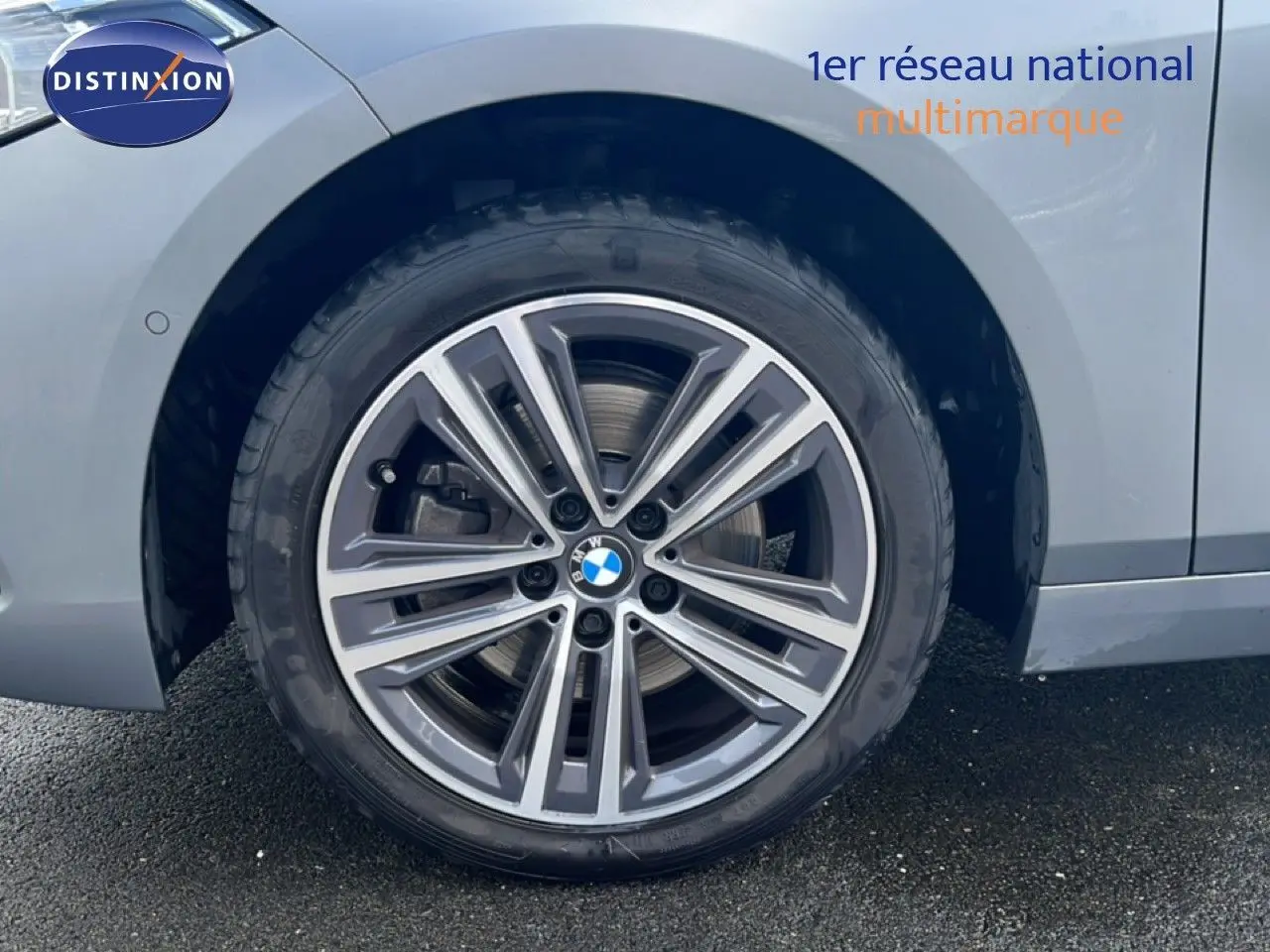 Gros plan sur la roue avant droite d'une BMW Série 1 116i 2022 en Frozen Pure Grey avec jante alliage bi-ton.