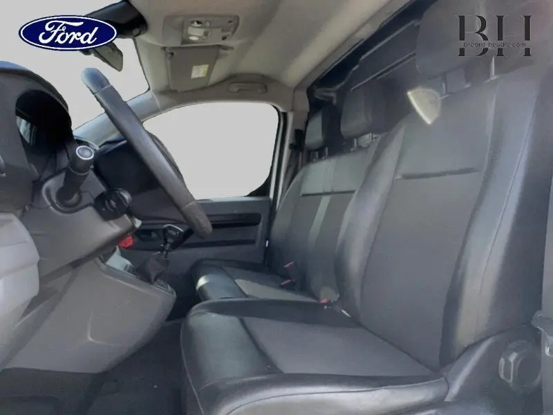 Vue intérieure côté conducteur du Peugeot Expert Fourgon 2020 avec sièges noirs en tissu Curitiba et tableau de bord gris.