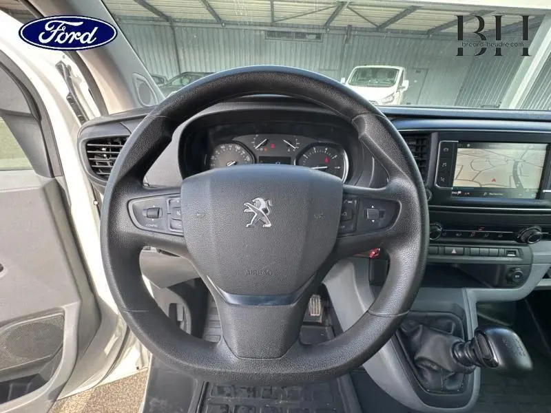 Vue intérieure centrée sur le volant Peugeot d'un Expert Fourgon blanc avec écran tactile de navigation visible à droite