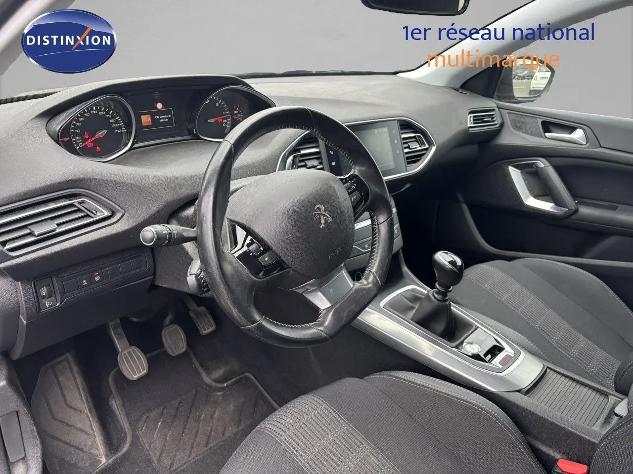 Vue intérieure côté conducteur de la Peugeot 308 1.5 BlueHDI 130 Allure avec volant cuir et boîte manuelle noire.