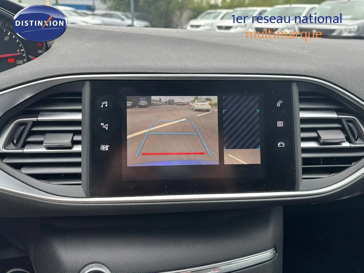 Écran central affichant la caméra de recul d'une Peugeot 308 Bleu Magnetic vue de l'intérieur côté tableau de bord.