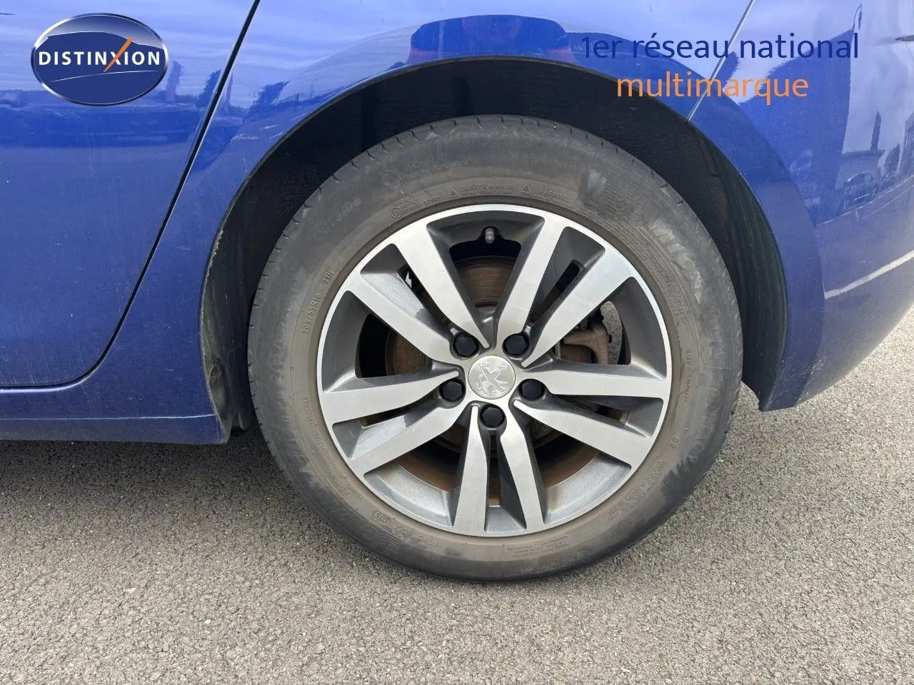 Gros plan sur la roue arrière droite d'une Peugeot 308 Bleu Magnetic, mettant en valeur la jante alliage distinctive.