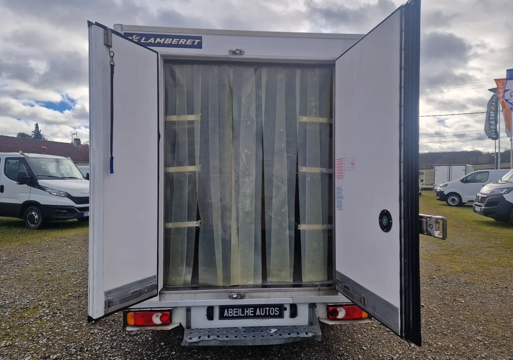 Vue arrière du Renault Master Plancher Cabine blanc avec portes frigorifiques ouvertes et rideaux plastiques transparents visibles.