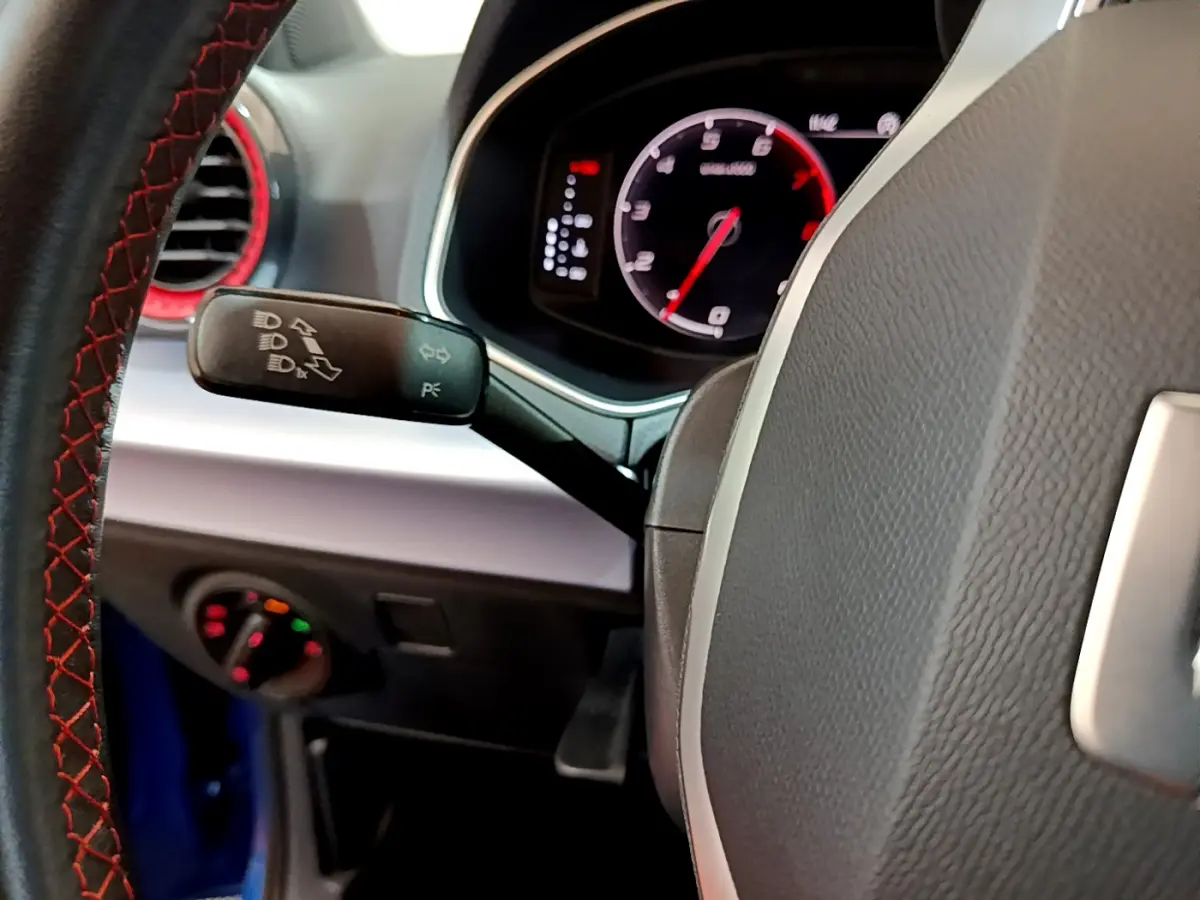 Gros plan sur le volant cuir avec surpiqûres rouges et tableau de bord numérique du SEAT Arona bleu 2022.