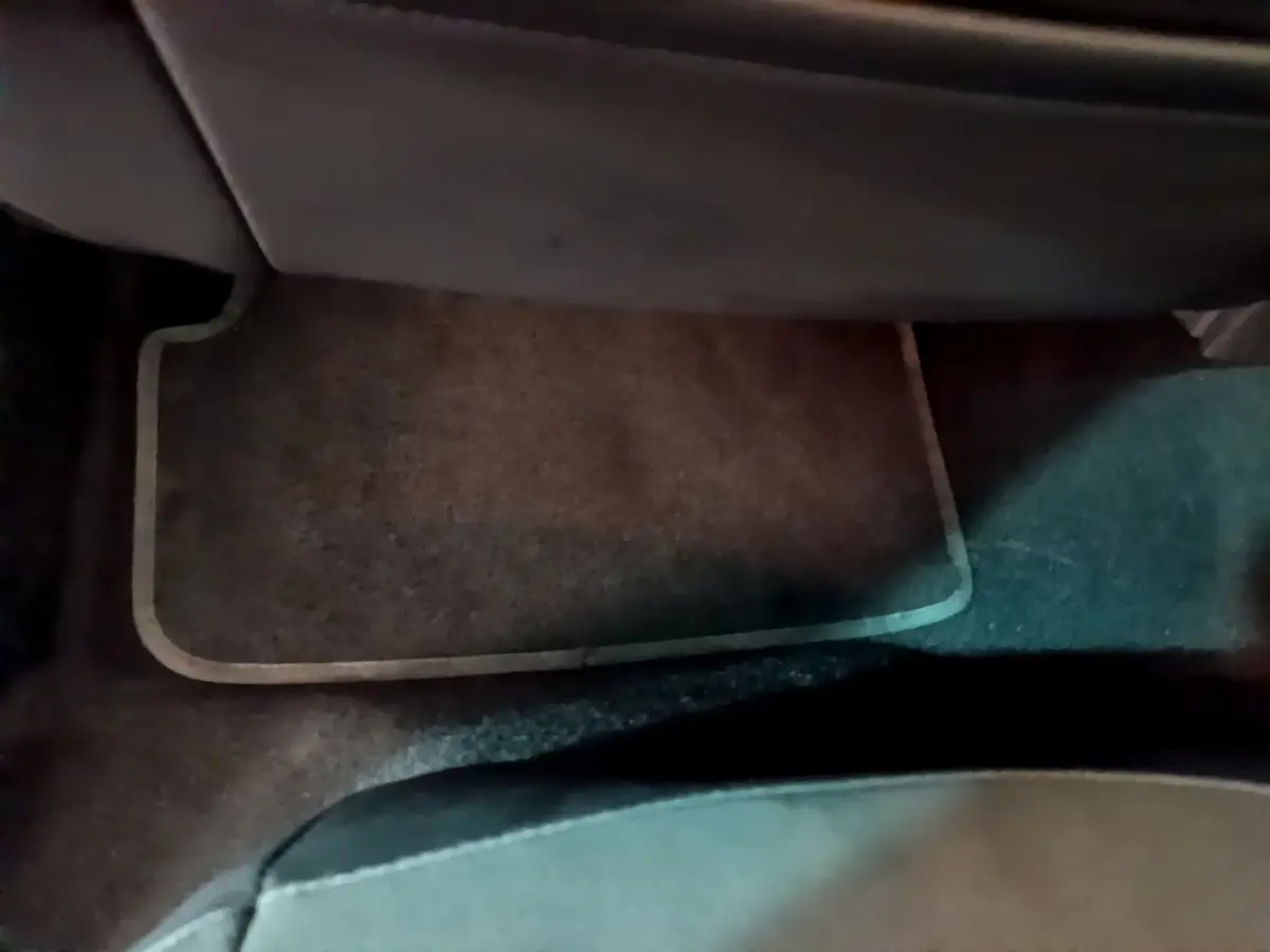 Tapis de sol marron sous le siège arrière d'un SEAT Arona bleu, vue intérieure côté passager arrière.