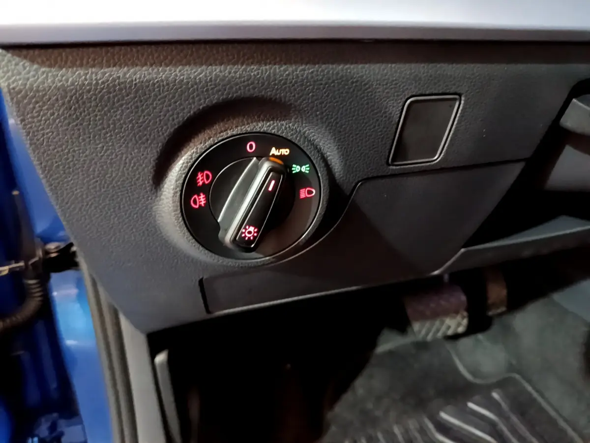 Gros plan sur le bouton de commande des phares dans l'habitacle côté gauche d'un SEAT Arona bleu 2022.