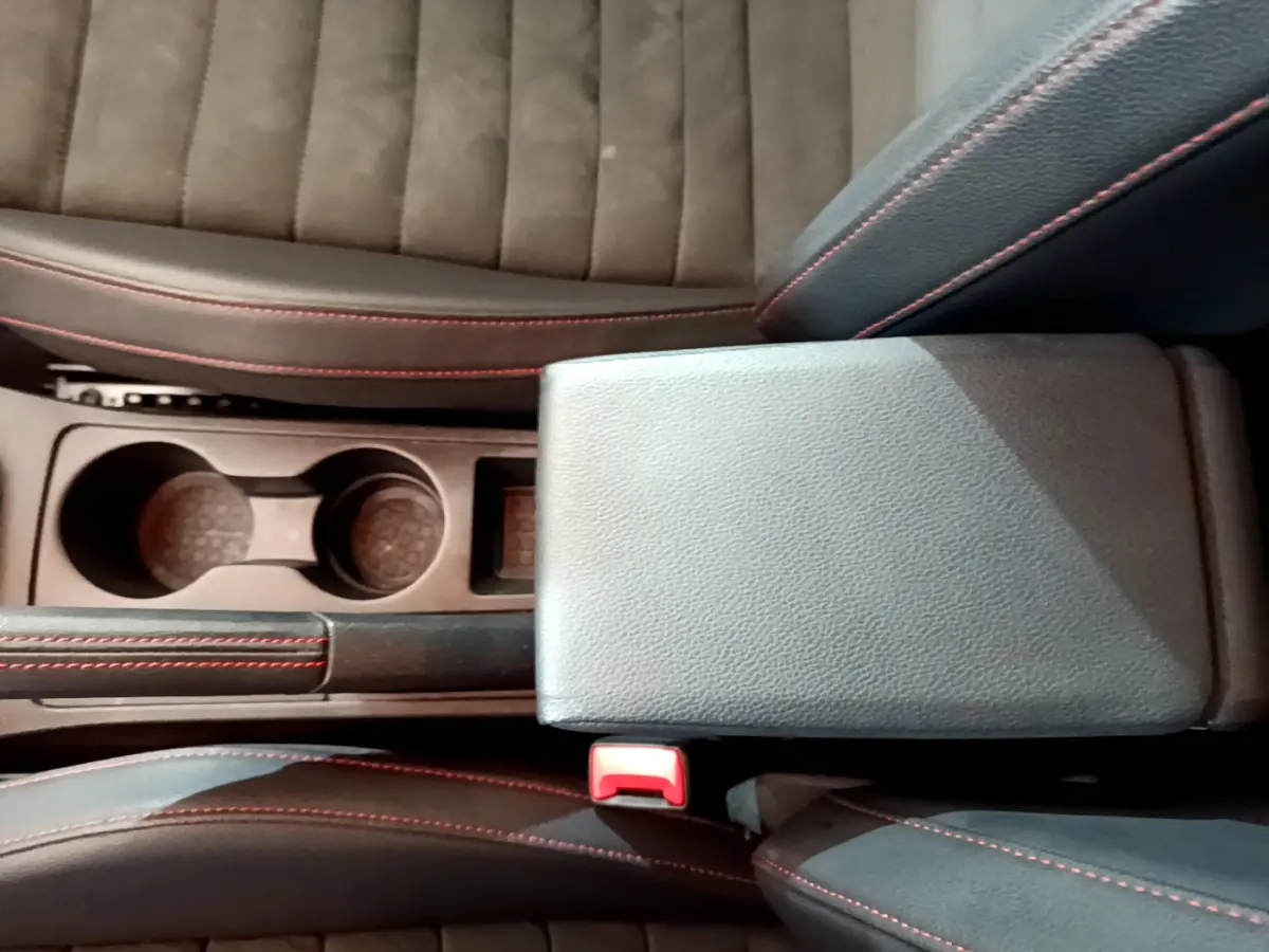 Vue plongeante sur la console centrale noire avec accoudoir et porte-gobelets du SEAT Arona bleu finition FR.