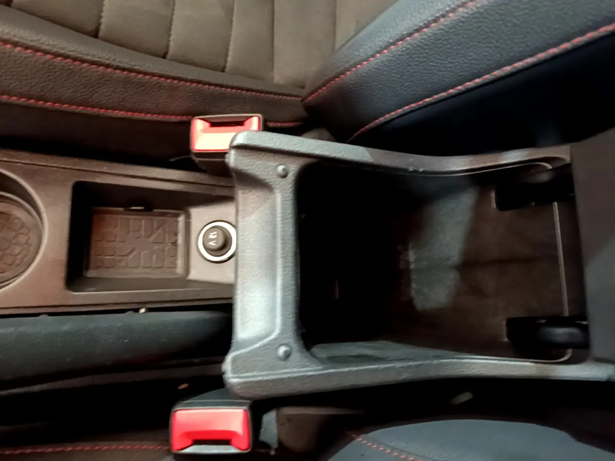 Vue plongeante sur l'accoudoir central ouvert et les sièges noirs avec surpiqûres rouges du SEAT Arona bleu 2022.